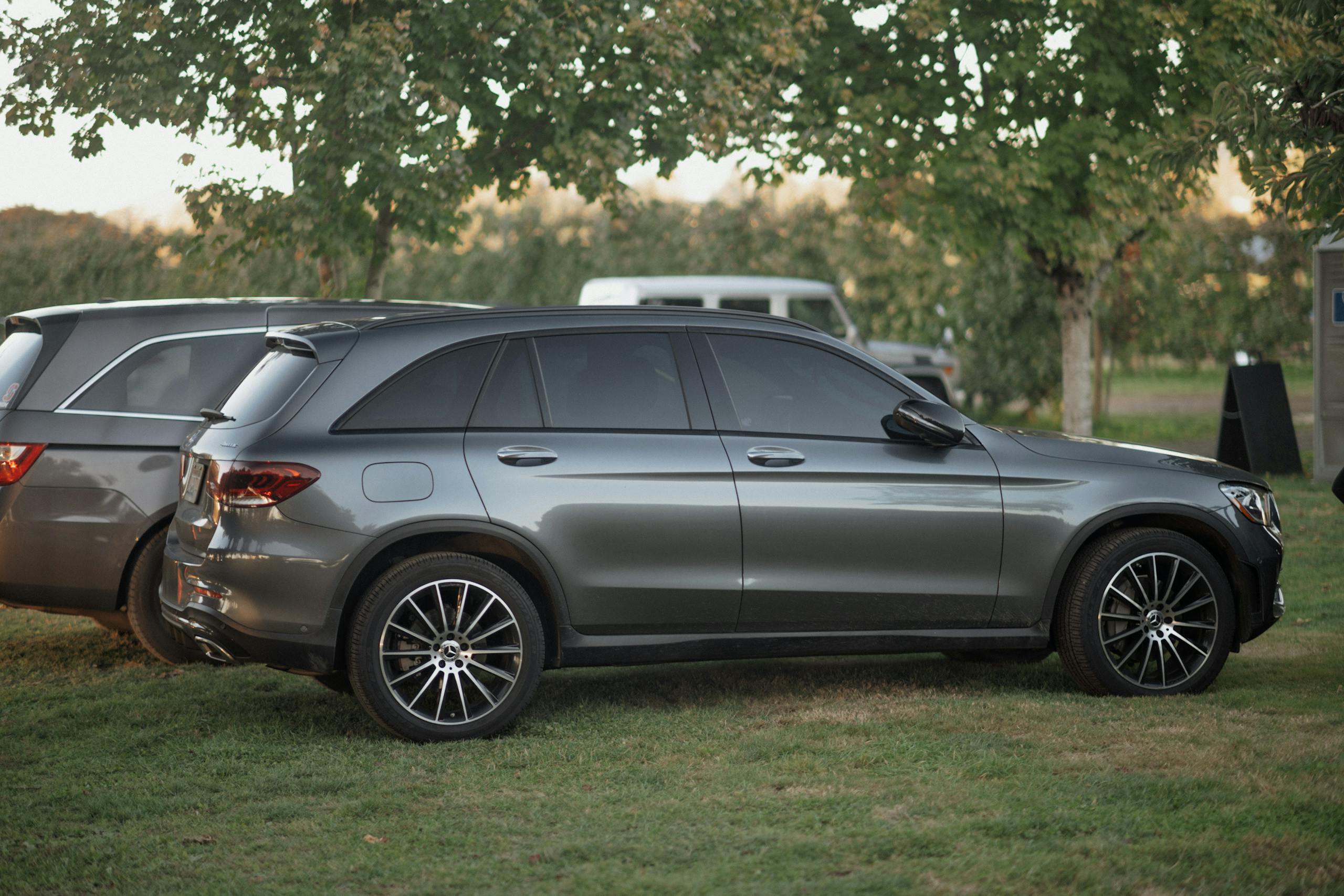 A modern gray SUV parked on grass in a scenic outdoor setting.